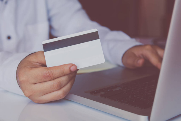 Mann hält Kreditkarte in der Hand und benutzt Laptop, um online zu bezahlen, online einzukaufen - Foto, Bild
