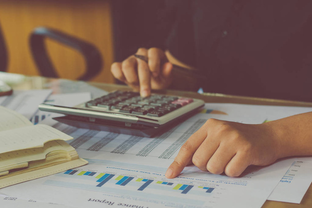 Ręką człowieka za pomocą Kalkulator finansowy z pisania sprawiają, Uwaga i analizowanie danych finansowych na biurku w domu - Zdjęcie, obraz