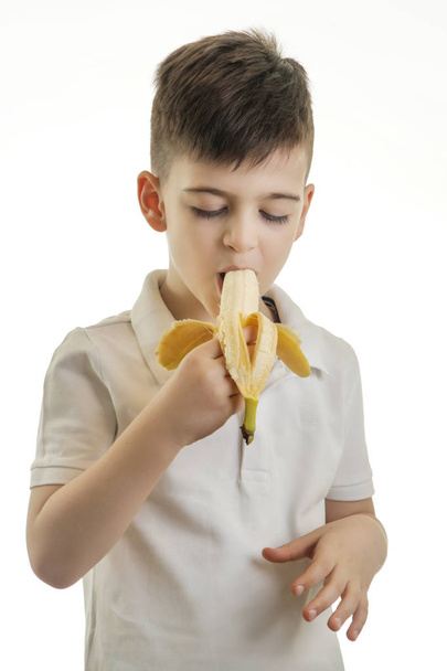 Студийный снимок мальчика, поедающего банан - концепция здорового питания
 - Фото, изображение