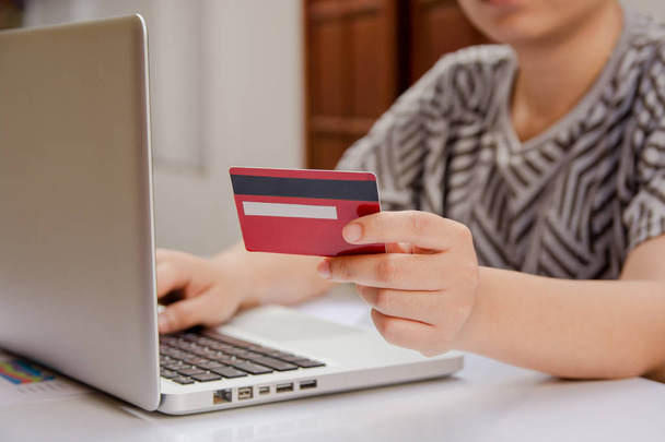 Frau hält Kreditkarte in der Hand und nutzt Laptop, um online zu bezahlen, Online-Shopping - Foto, Bild