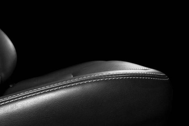 Black leather interior of the luxury modern car. Perforated Leather comfortable seats with stitching isolated on black background. Modern car interior details. Car detailing. Car inside - Foto, afbeelding