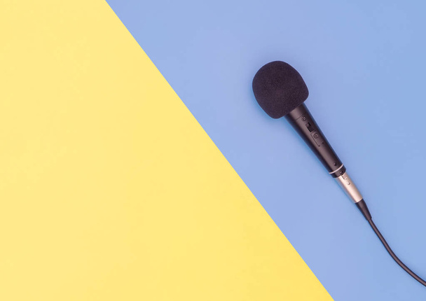 Fekete mikrofon kék sárga háttérrel zenei koncepció - Fotó, kép