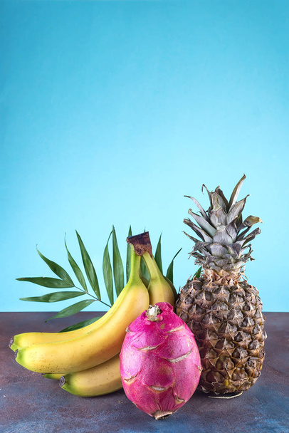 Assorted tropical fruits pineapple, mango, dragon fruit, on stone background. Group of exotic tropical fruits. Vegetarian healthy concept, copy space - Photo, Image