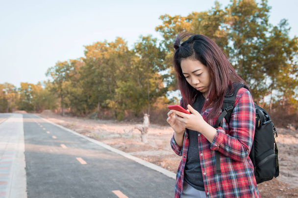Kobieta za pomocą smartfona znaleźć kierunki przez Side of the Road - Zdjęcie, obraz