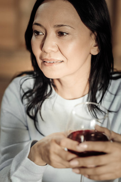 Pleasant middle aged woman sitting with a glass of wine - Fotoğraf, Görsel
