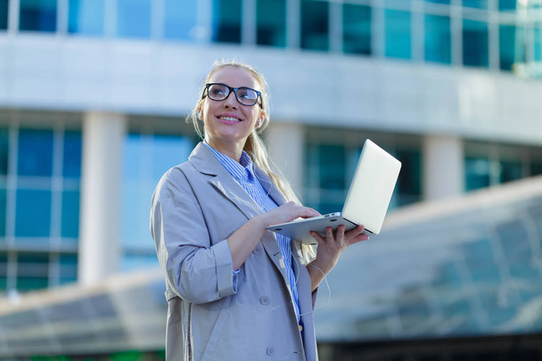 Business woman standing with a laptop in the city center - Foto, imagen