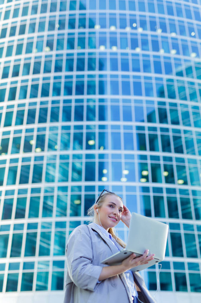 Business woman standing with a laptop in the city center - Photo, image