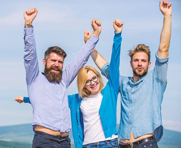 Company reached top. Company of three happy colleagues or partners celebrating success, sky background. Success concept. Men with beard in formal shirts and blonde in eyeglasses as successful team - Фото, зображення