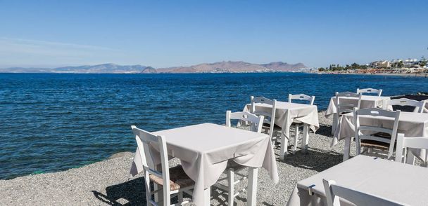 Restauracja biały tabel na plaży latem - podróże, wakacje i lato koncepcja. Doskonały lunch z widokiem na morze - Zdjęcie, obraz