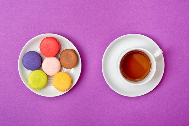 Colorful sweet macaroons and a cup of tea. Delicious breakfast. Top view. - Фото, изображение