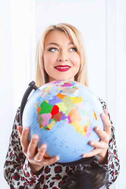 beautiful cheerful smiling blonde woman travel agent holding globe in her hands  - Photo, Image