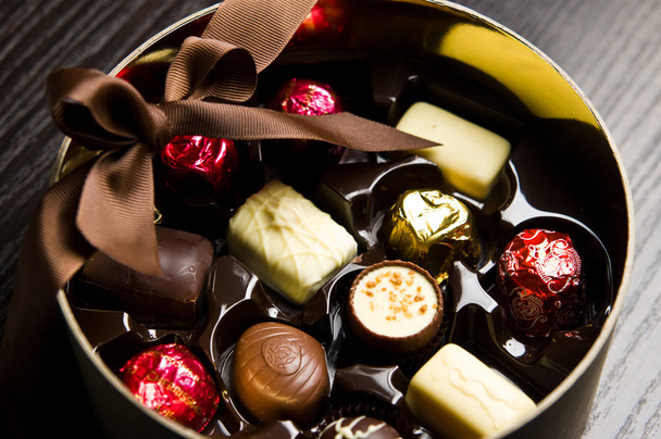 Ακόμη ζωή του ένα κομψό στρογγυλό κουτί με νόστιμα βελγικές σοκολάτες. - Φωτογραφία, εικόνα