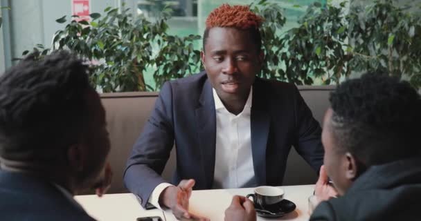 African man proves something to his friends in a cafe - Séquence, vidéo