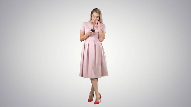 Portret van een vrij lachende meisje in zomer kleding met behulp van de mobiele telefoon, SMS bericht op verloop achtergrond. - Foto, afbeelding