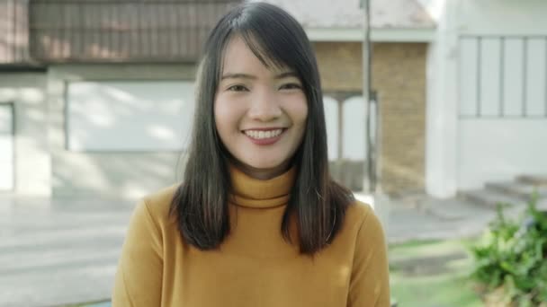 fröhliche schöne junge asiatische Frau, die glücklich lächelnd in die Kamera lächelt, während sie abends auf der Straße in der Innenstadt unterwegs ist. Lifestyle-Reisekonzept für Touristen. Porträt mit Blick auf die Kamera. - Filmmaterial, Video