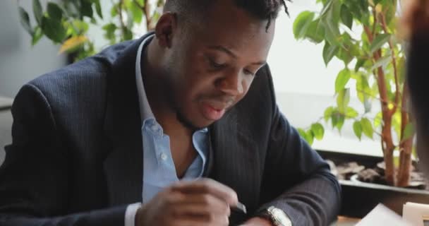 African businessman signs a contract in a cafe - Záběry, video
