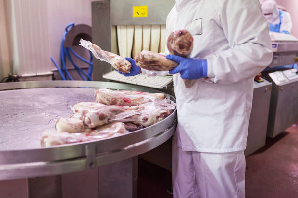 operaio con abbigliamento igienico utilizzando la confezionatrice sottovuoto del laboratorio di taglio carne
 - Foto, immagini