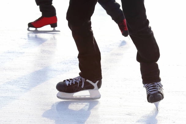 Füße verschiedener Menschen, die auf der Eisbahn Schlittschuh laufen - Foto, Bild