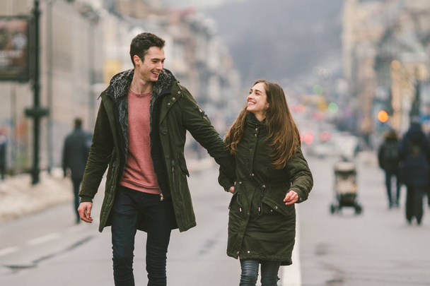 fiatal pár, a heteroszexuális fiú és a lány kaukázusi állampolgárságú, szerető pár, séta körül a középső, az ország európai város út közepén osztott lane. Szeretet és a romantika téma. - Fotó, kép
