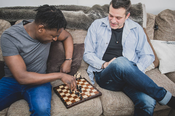 A gay couple enjoying time indoors at home, playing chess.  - Foto, Bild