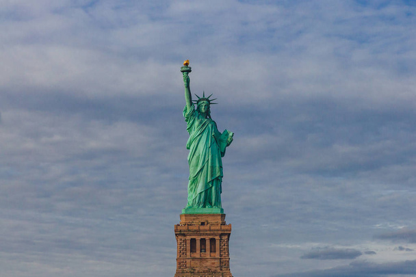 Вид Статуи Свободы на фоне неба и облаков в Нью-Йорке, США
 - Фото, изображение