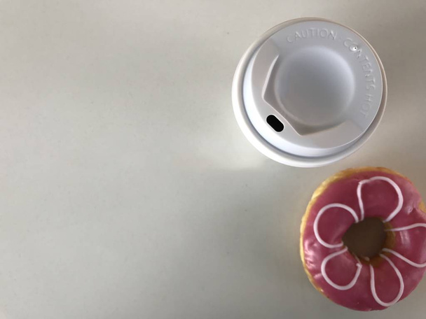 обрезанный снимок белой чашки горячего кофе и цветущего розового пончика на белом фоне в студии
 - Фото, изображение