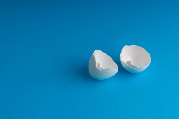 Broken eggshell on the blue background with selective focus - Photo, Image