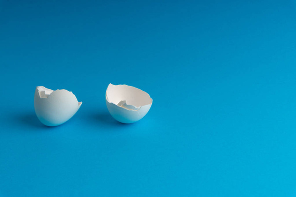 Broken eggshell on the blue background with selective focus - Foto, imagen