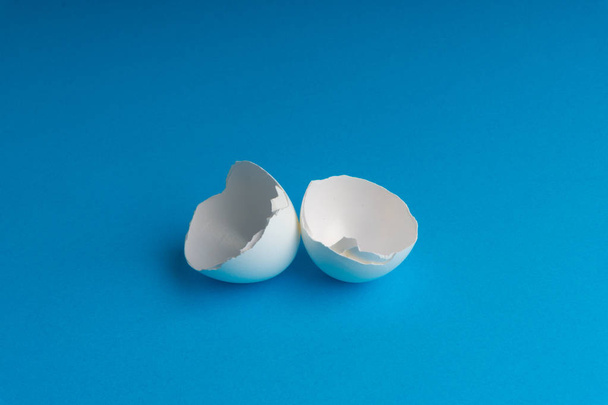 Broken eggshell on the blue background with selective focus - Foto, Imagen