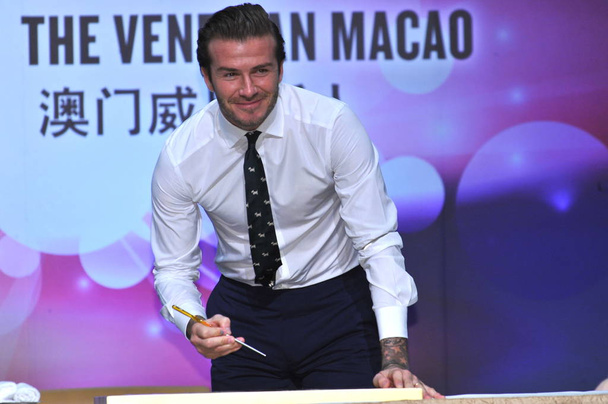 English football star David Beckham smiles as he prepares to signs an autograph during a press conference at the Venetian Macao Resort Hotel in Macau, China, 22 November 2013 - Photo, image