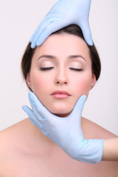 Rubber gloves touching face of young woman close up - Фото, изображение