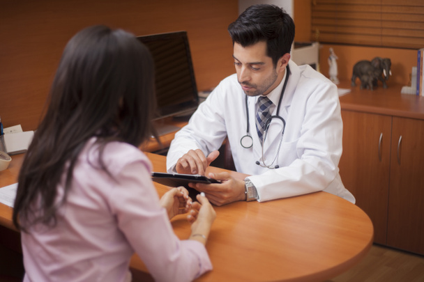 Férfi orvos írásban valamit le, míg a beteg beszél egy szobában - Fotó, kép