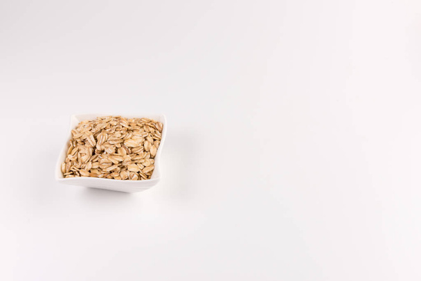 Dry rolled oatmeal in bowl isolated on white background. - Fotó, kép