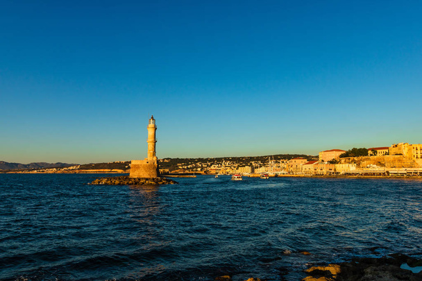 Vízparti panorámás velencei kikötő és a világítótorony a régi kikötő, Chania napnyugtakor, Kréta, Görögország. - Fotó, kép