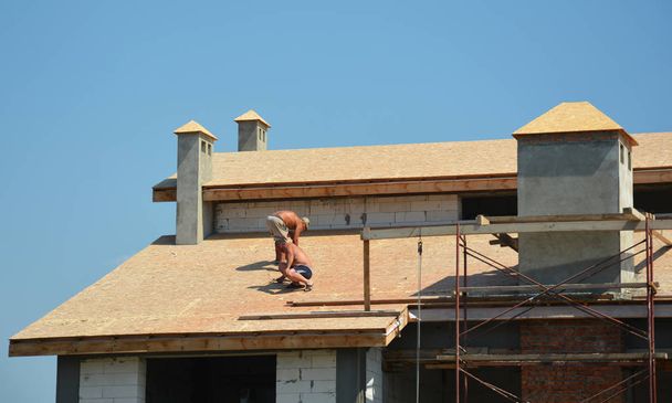 Roofing construction works by roofing contractors. Roofers preparing house roof for asphalt shingles installation. - Photo, Image
