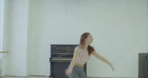 Crazy expressive female dancer with straight flying brown hair fully engrossed in modern dance, performing passionate dance moves and playing piano emotionally in dance studio during rehearsal. - Materiał filmowy, wideo