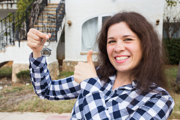 Ιδιοκτησίας, ακίνητη περιουσία, να αγοράσουν και να νοικιάσουν έννοια - γυναίκα με κλειδιά που στέκεται έξω από το νέο σπίτι - Φωτογραφία, εικόνα