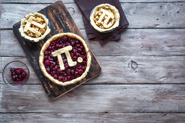 Pi Day Cherry and Apple Pies - making homemade traditional various Pies with Pi sign for March 14th holiday, on rustic wooden background, top view, copy space. - Фото, изображение