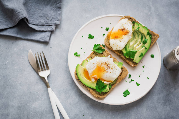 Avocado Sandwiches with Poached Eggs - sliced avocado and egg on toasted bread for healthy breakfast or snack. - Foto, imagen
