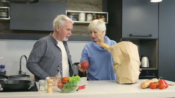 Elder couple unpacking fruits and vegetables from brown grocery bag. - Filmagem, Vídeo