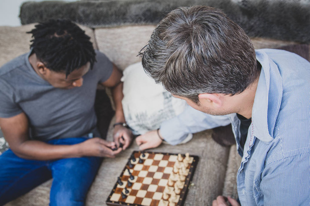 Una pareja gay disfrutando del tiempo en casa, jugando ajedrez
.  - Foto, Imagen