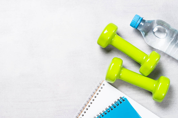 Dumbbells, notepad, water and apple top view.  - Foto, Imagem