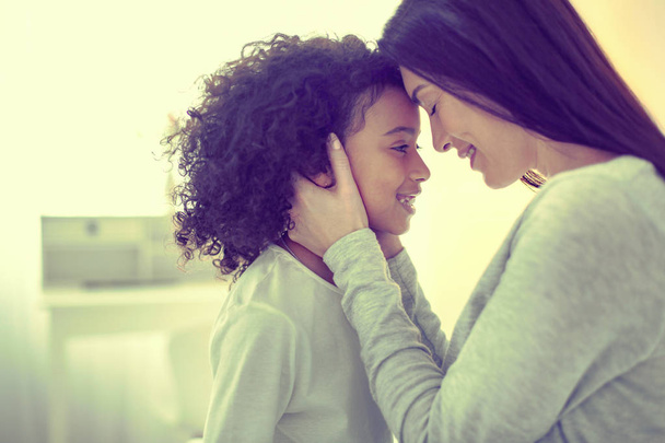 Little mulatto girl and her adoptive mom living in total harmony. - Foto, imagen