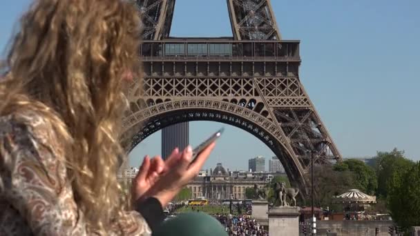 Όμορφη γυναίκα με τα μαλλιά στον άνεμο αποτυπώνει στιγμές και αναμνήσεις κοντά στον πύργο του Άιφελ - Πλάνα, βίντεο