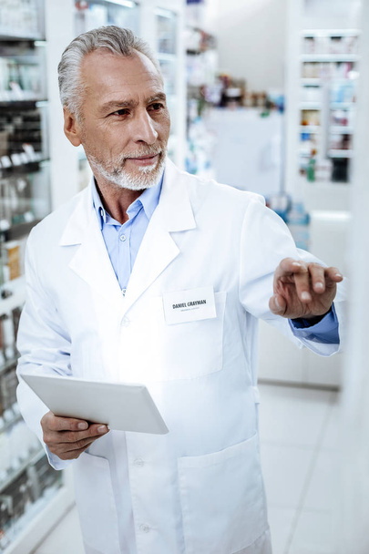 Director of a drugstore in a white coat looking attentive - Foto, imagen