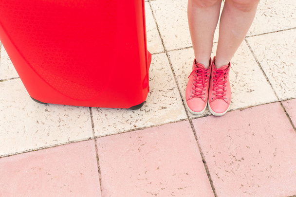 Seyahat, turizm ve insanlar kavramı - kırmızı bavul ve kırmızı spor ayakkabı ayaklarda yakın - Fotoğraf, Görsel
