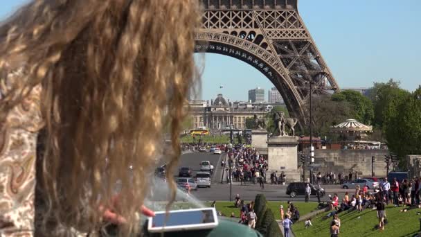 Όμορφη γυναίκα με τα μαλλιά στον άνεμο αποτυπώνει στιγμές και αναμνήσεις κοντά στον πύργο του Άιφελ - Πλάνα, βίντεο