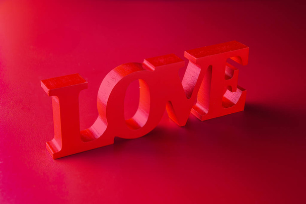 Achtergrondafbeelding op het thema van de Love.Valentine dag. Houten woord Love op rode achtergrond. - Foto, afbeelding