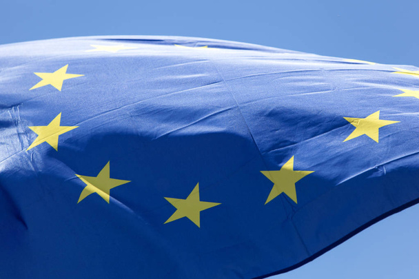 Европейский флаг вблизи, перед голубым небом
 - Фото, изображение