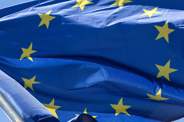 Европейский флаг вблизи, перед голубым небом
 - Фото, изображение